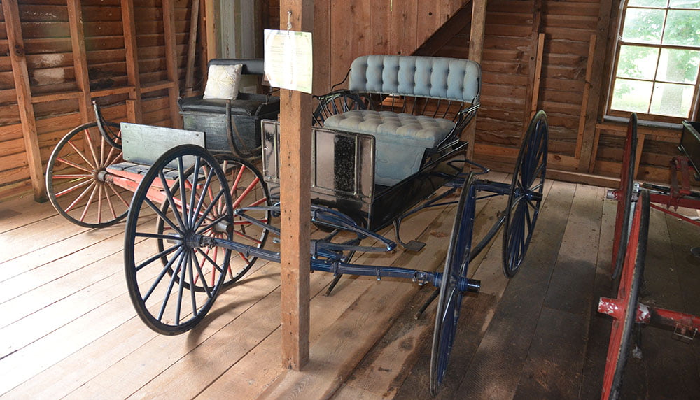 A few old horse-drawn carriages in a barn.