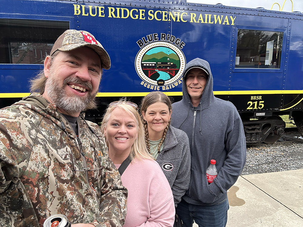 The author, his wife, and their friends standing in front of the Blue Ridge Scenic Railway locomotive.